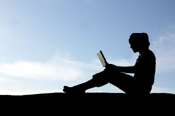 Silhouette of laptop user with sky in background
